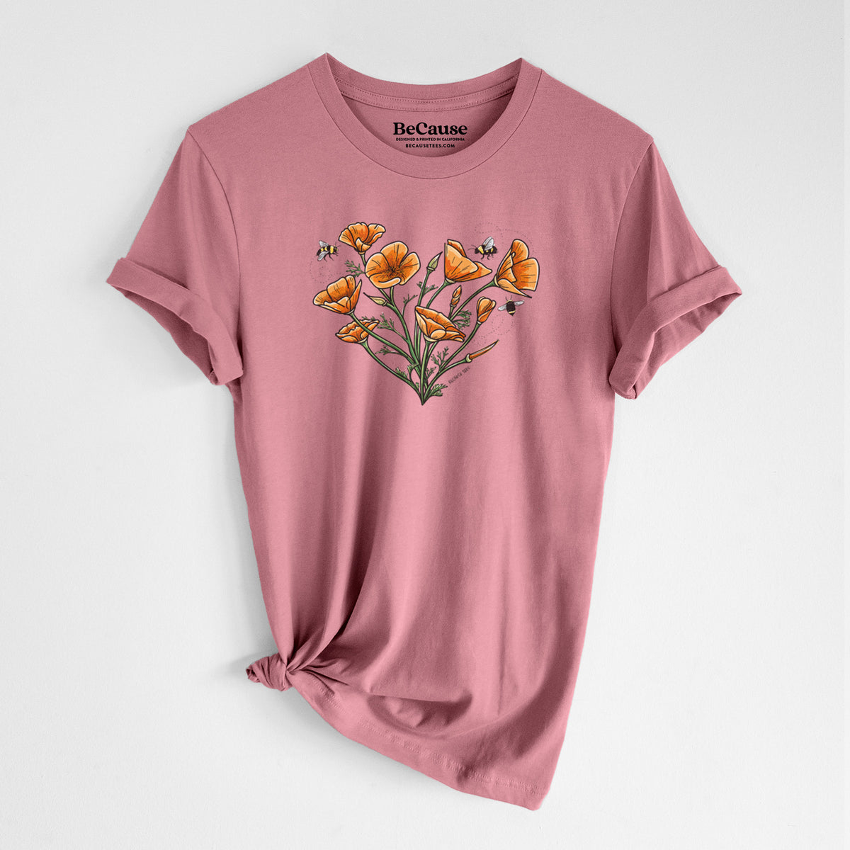 Mauve pink lightweight cotton t-shirt laid flat with the sleeves rolled, printed with a full-color bouquet of orange California poppies arranged in a heart shape, with small bees.