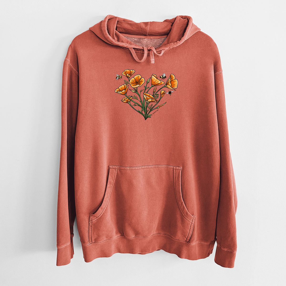 Amber orange pigment dyed hoodie laid flat, printed with a full-color bouquet of orange California poppies arranged in a heart shape, with small bees.