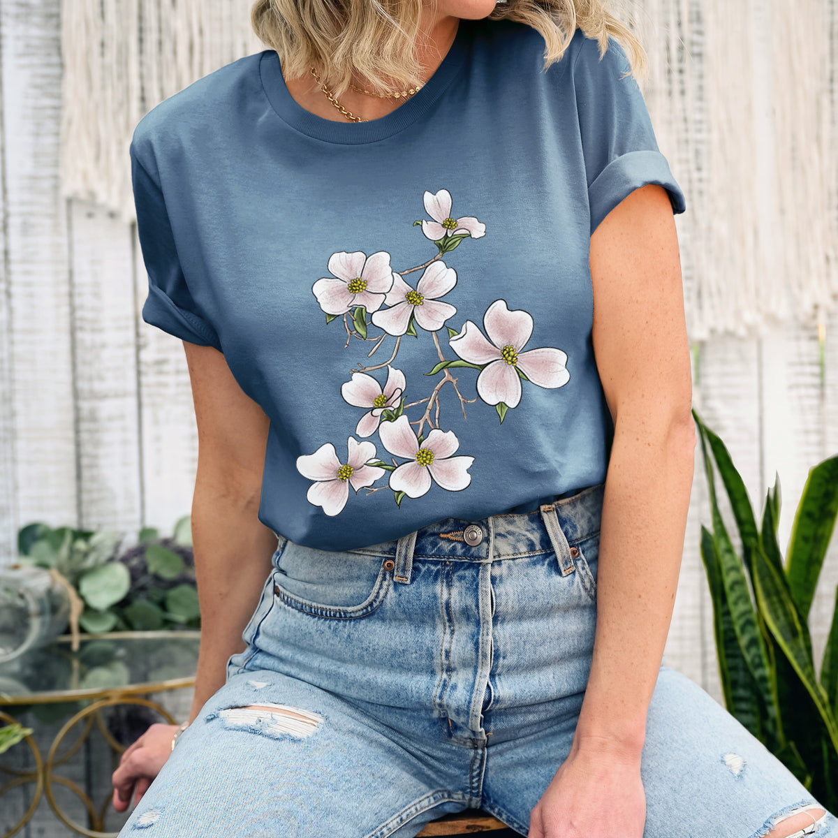 Woman wearing a steel blue lightweight cotton t-shirt printed with a full-color illustration of pink and white dogwood blossoms on a branch.