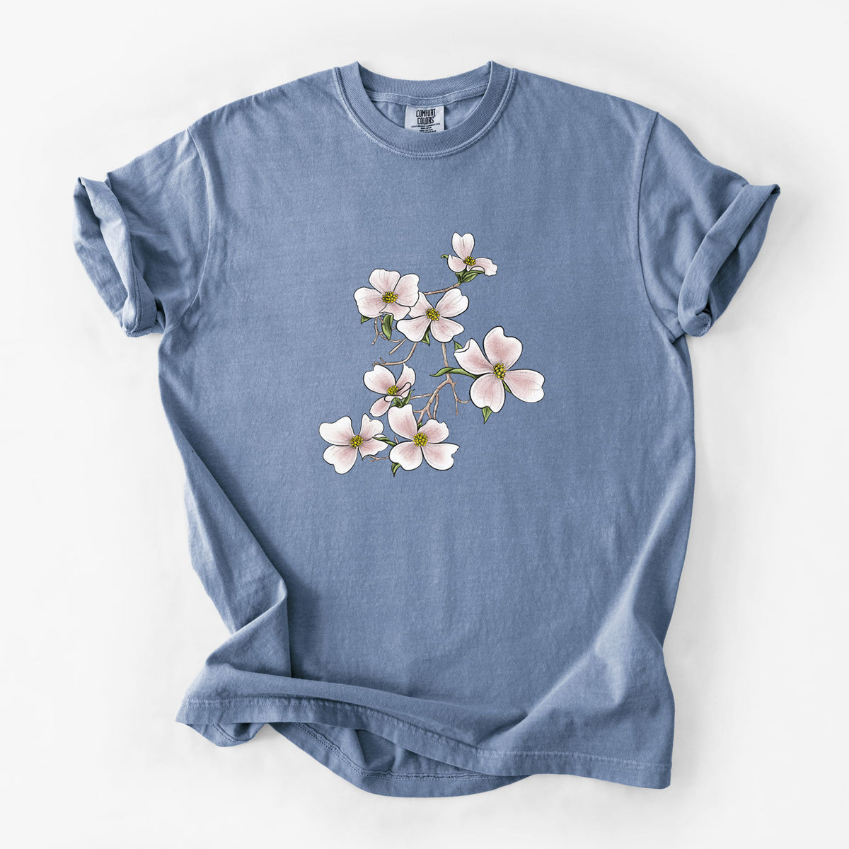 Blue jean Comfort Colors t-shirt laid flat, printed with a full-color illustration of pink and white dogwood blossoms on a branch.