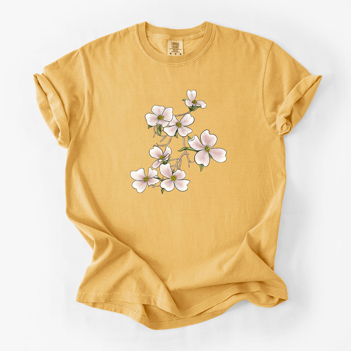 Golden wheat yellow Comfort Colors t-shirt laid flat, printed with a full-color illustration of pink and white dogwood blossoms on a branch.