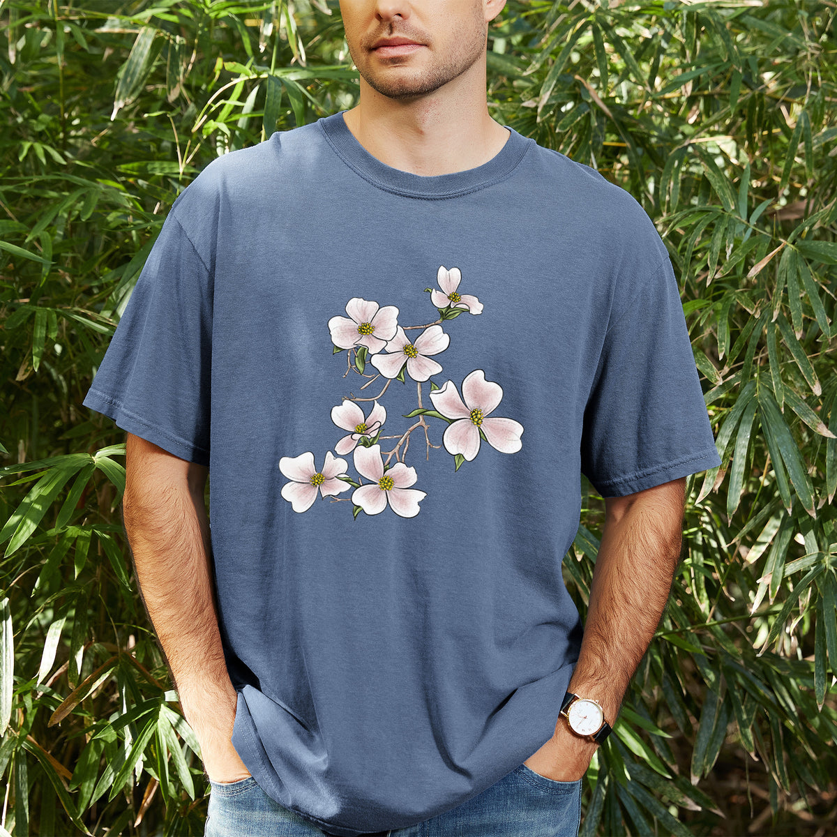 Man wearing a Comfort Colors t-shirt printed with a full-color illustration of pink and white dogwood blossoms on a branch, outdoors.