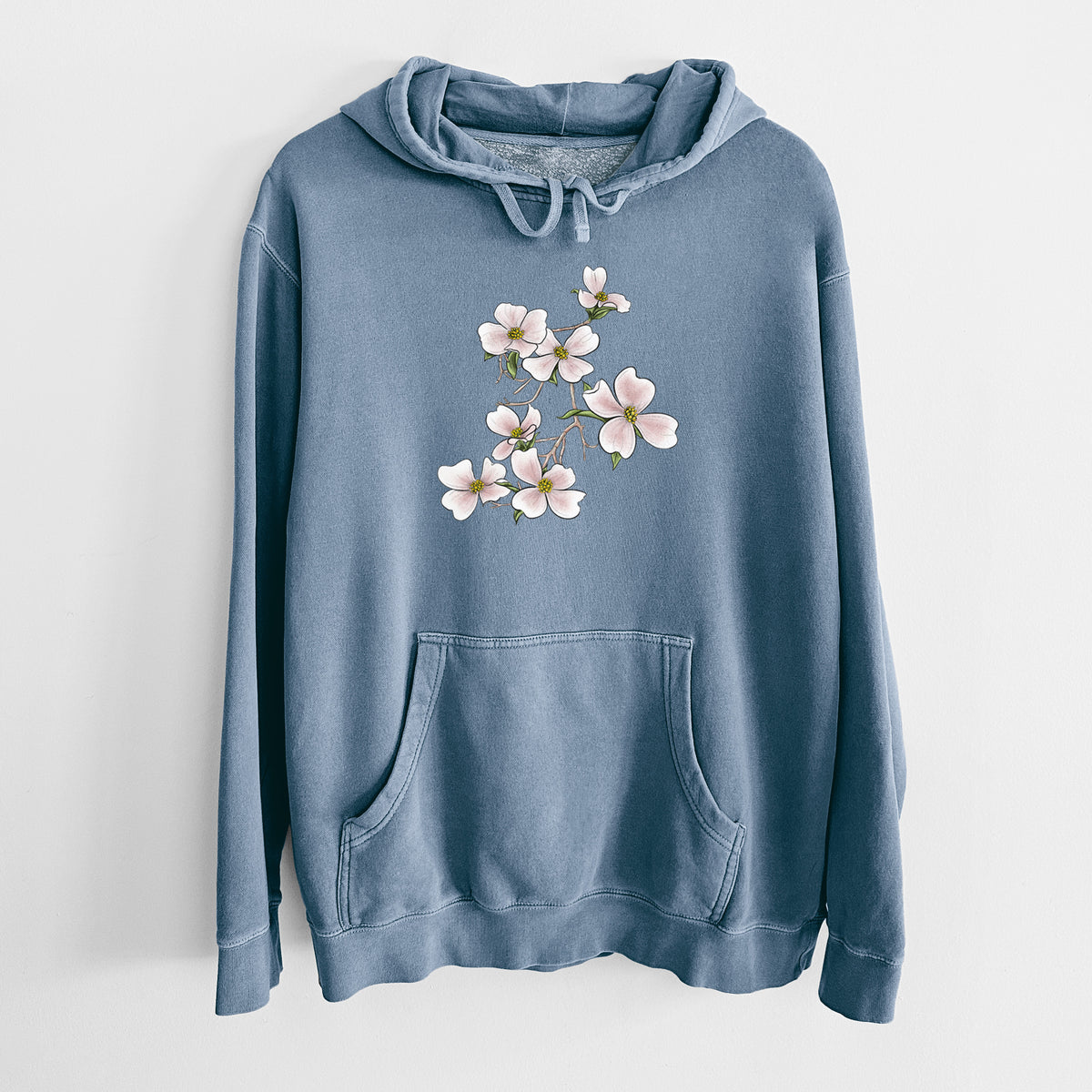 Slate blue pigment dyed hoodie laid flat, printed with a full-color illustration of pink and white dogwood blossoms on a branch.