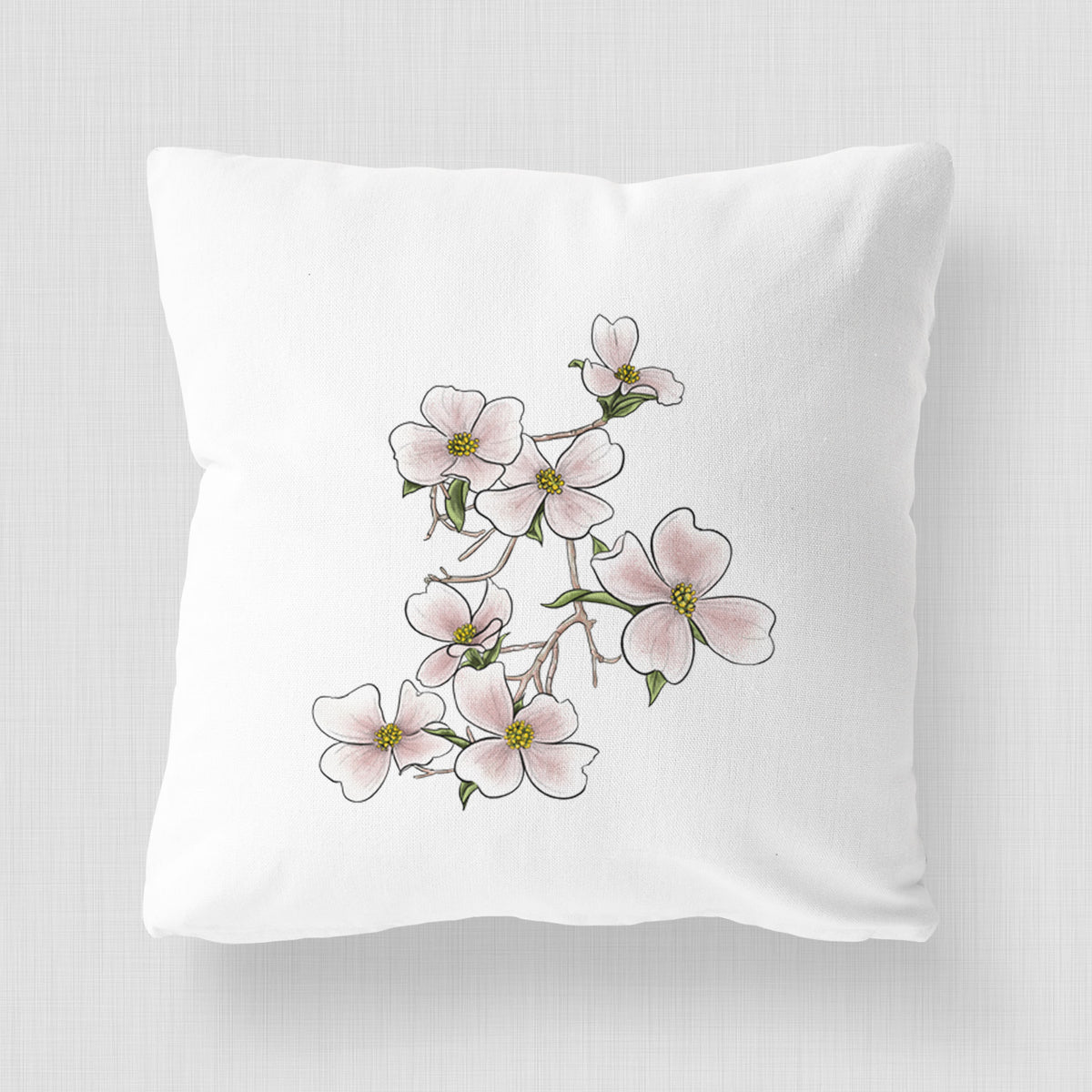 White pillow cover printed with a full-color illustration of pink and white dogwood blossoms on a branch.
