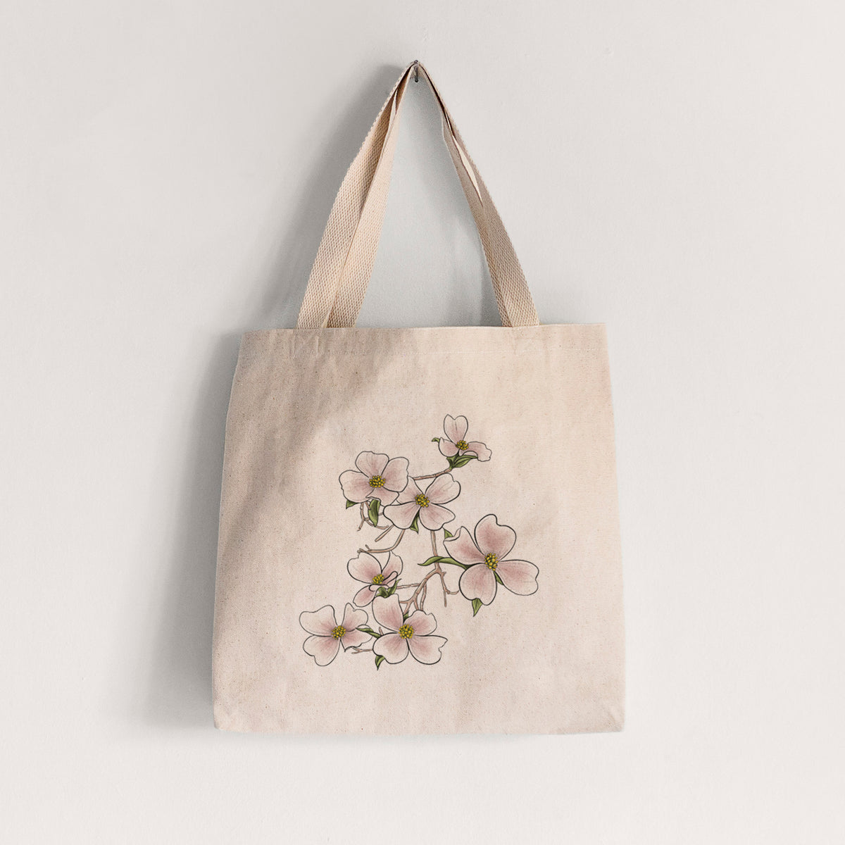 Natural canvas tote bag printed with a full-color illustration of pink and white dogwood blossoms on a branch.