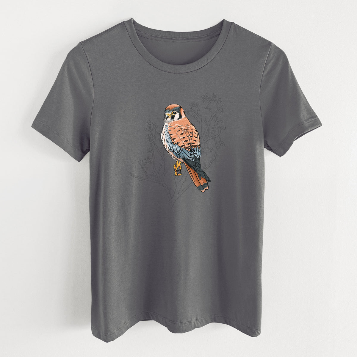 Asphalt women's relaxed fit cotton t-shirt laid flat, printed with a full-color illustration of an American kestrel perched among pale branches.