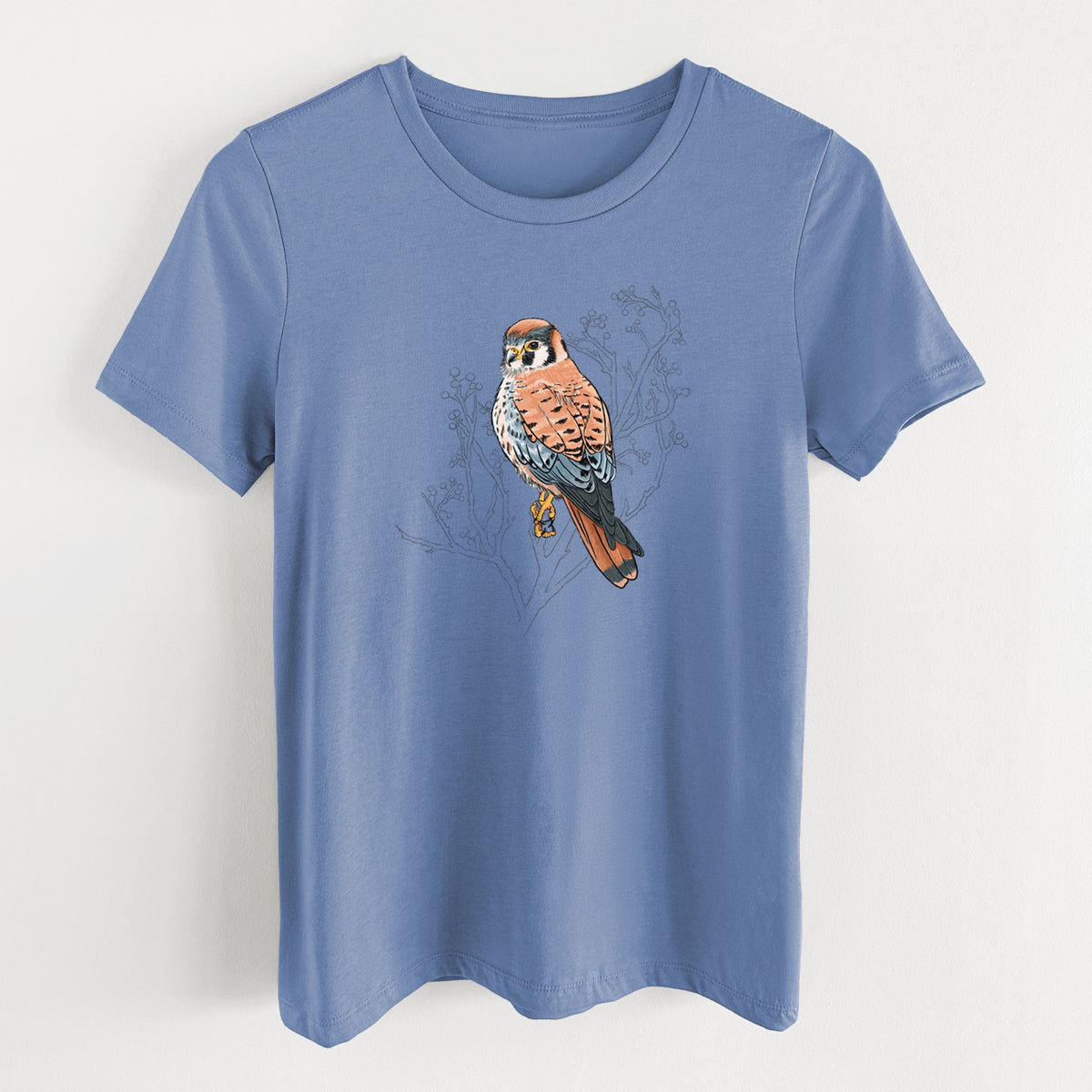 Blue bell women's relaxed fit cotton t-shirt laid flat, printed with a full-color illustration of an American kestrel perched among pale branches.