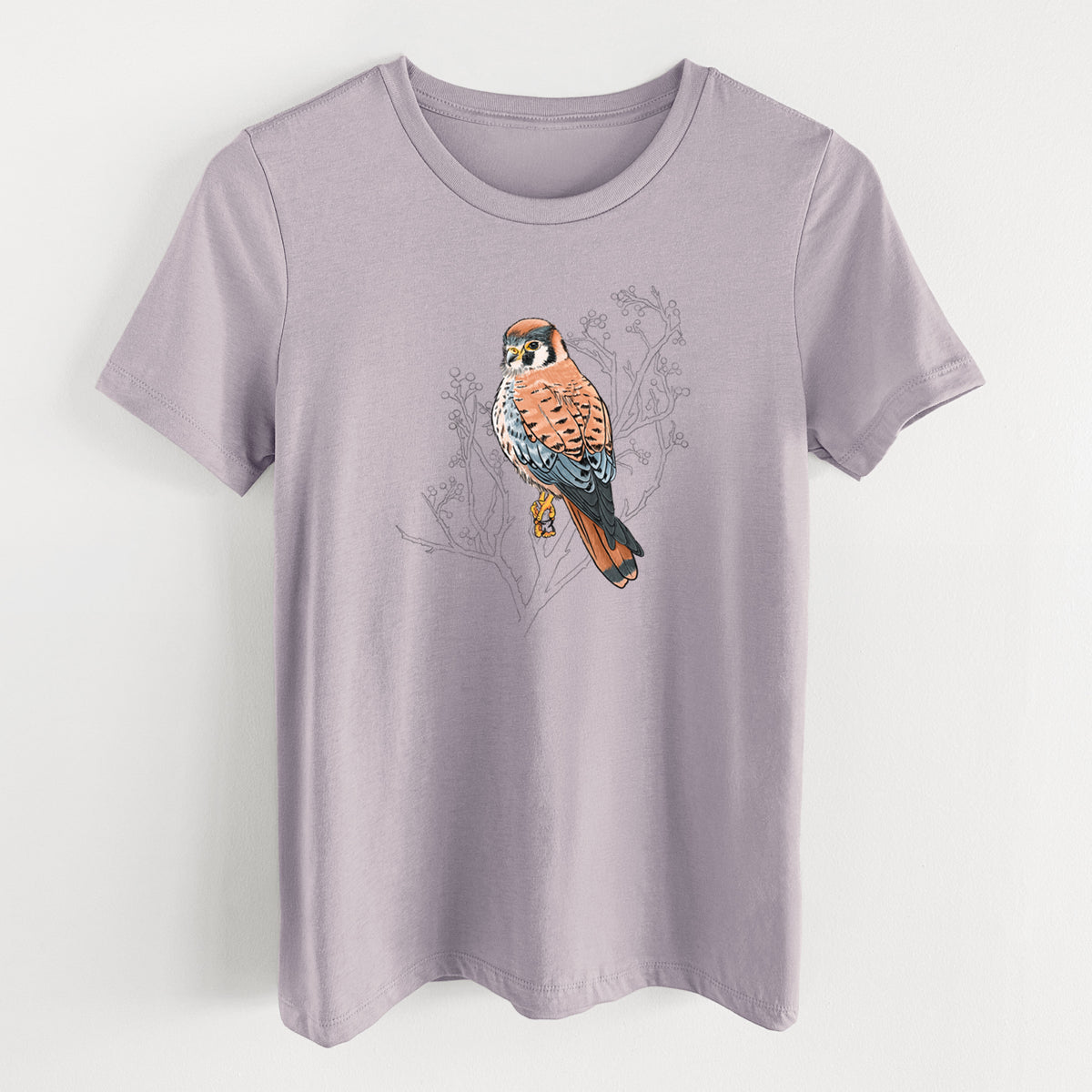 Light violet women's relaxed fit cotton t-shirt laid flat, printed with a full-color illustration of an American kestrel perched among pale branches.