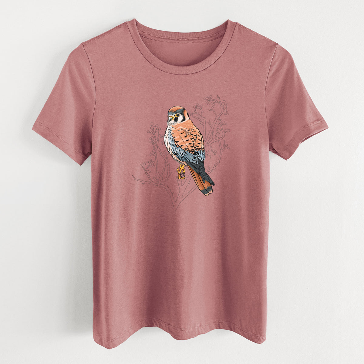 Mauve pink women's relaxed fit cotton t-shirt laid flat, printed with a full-color illustration of an American kestrel perched among pale branches.