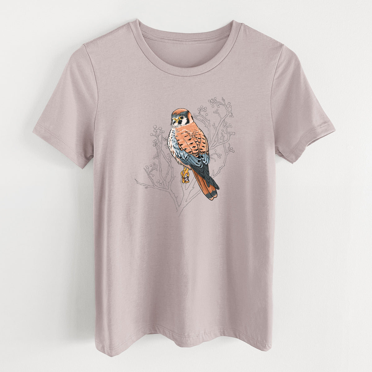 Pink gravel women's relaxed fit cotton t-shirt laid flat, printed with a full-color illustration of an American kestrel perched among pale branches.