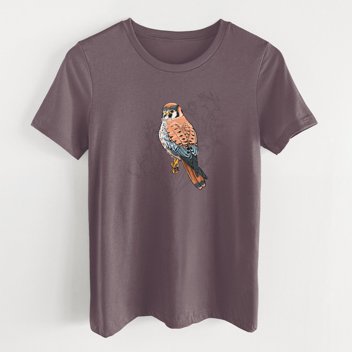 Purple storm women's relaxed fit cotton t-shirt laid flat, printed with a full-color illustration of an American kestrel perched among pale branches.