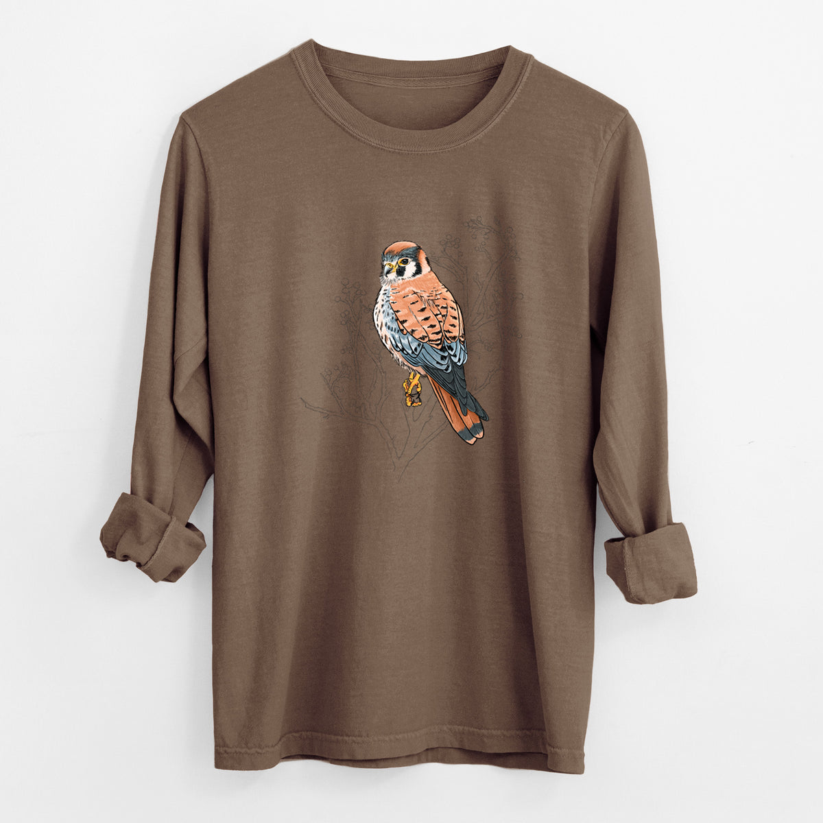 Espresso brown Comfort Colors long sleeve shirt laid flat with the cuffs rolled, printed with a full-color illustration of an American kestrel perched among pale branches.