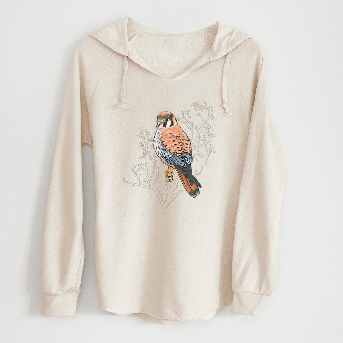 Bone cream women's Cali Wave hooded sweatshirt laid flat, printed with a full-color illustration of an American kestrel perched among pale branches.