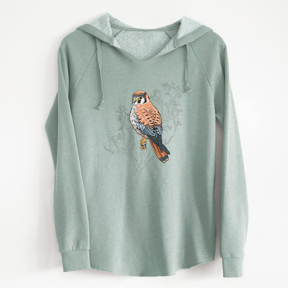Sage green women's Cali Wave hooded sweatshirt laid flat, printed with a full-color illustration of an American kestrel perched among pale branches.