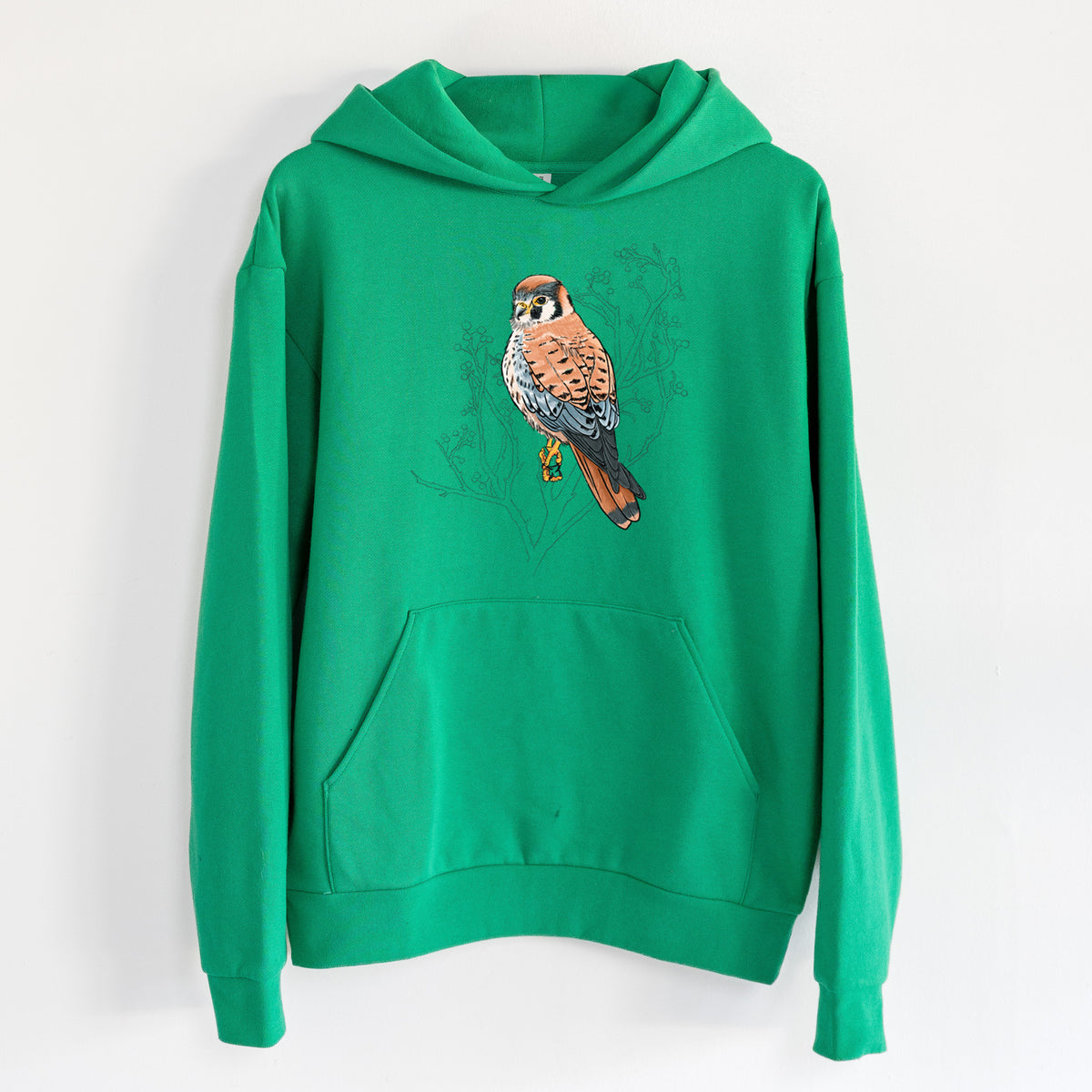 Vibrant American Kestrel - Falco sparverius - Statement Midweight Hoodie in Kelly Green, hanging on a white wall, with a front kangaroo pocket and no drawcords.