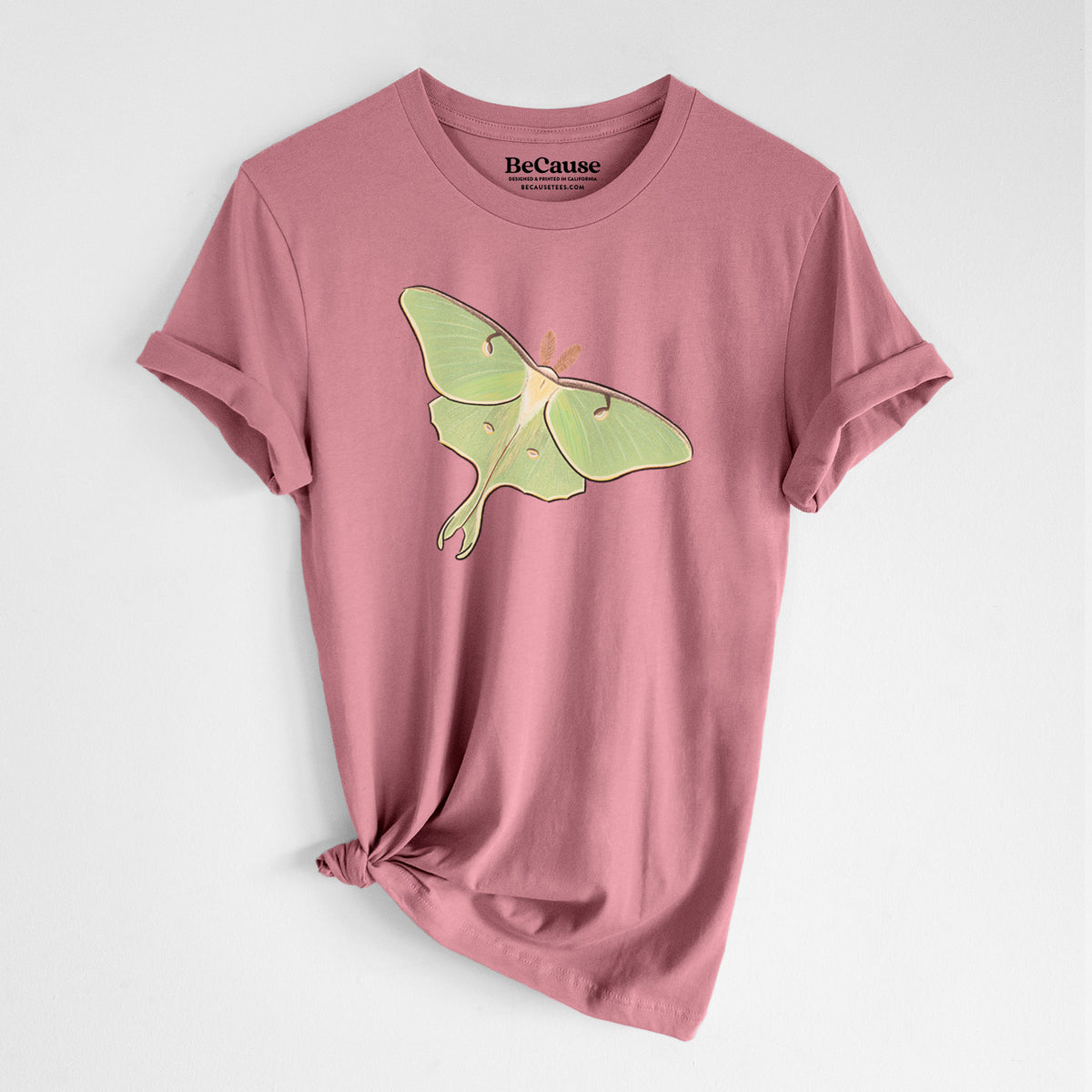 Mauve pink lightweight cotton t-shirt laid flat with the sleeves rolled, printed with a full-color illustration of a pale green luna moth with long tails on its wings.