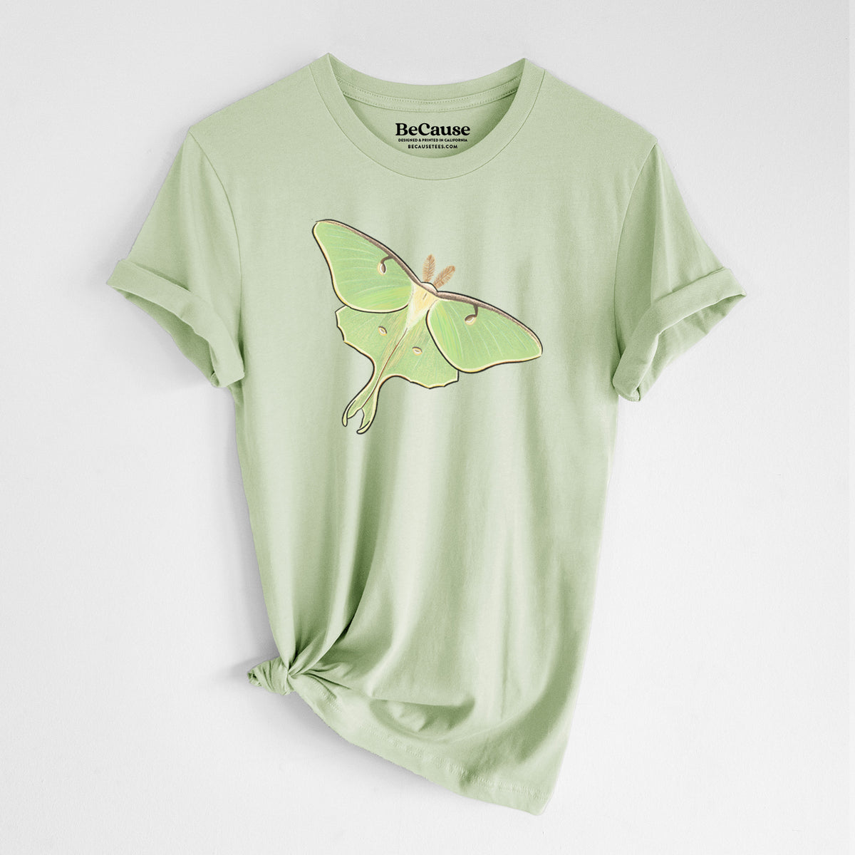 Spring green lightweight cotton t-shirt laid flat with the sleeves rolled, printed with a full-color illustration of a pale green luna moth with long tails on its wings.