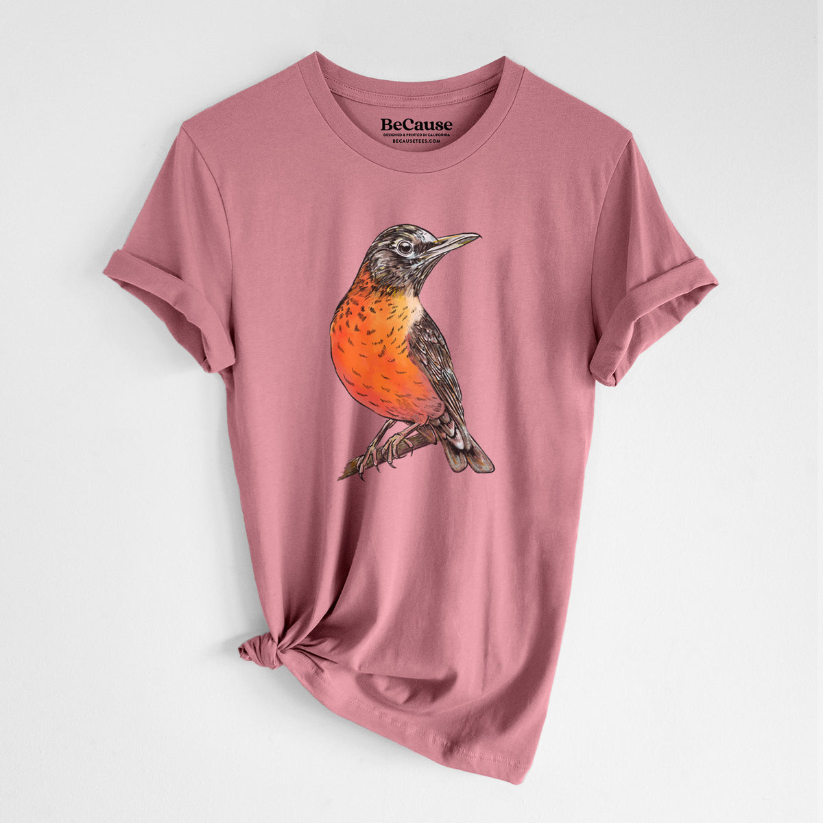 Mauve pink lightweight cotton t-shirt laid flat with the sleeves rolled, printed with a full-color illustration of an American robin with an orange breast perched on a branch.