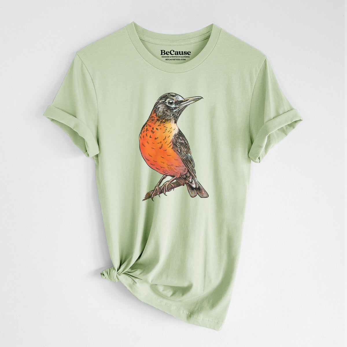 Spring green lightweight cotton t-shirt laid flat with the sleeves rolled, printed with a full-color illustration of an American robin with an orange breast perched on a branch.