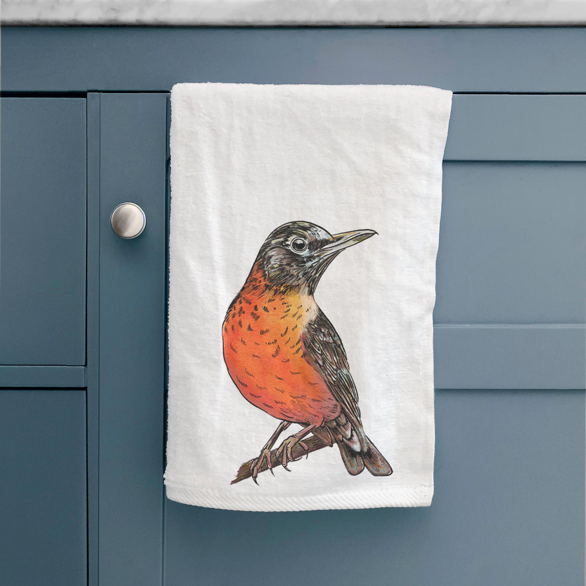 White hand towel printed with a full-color illustration of an American robin with an orange breast perched on a branch, hanging on a cabinet door.