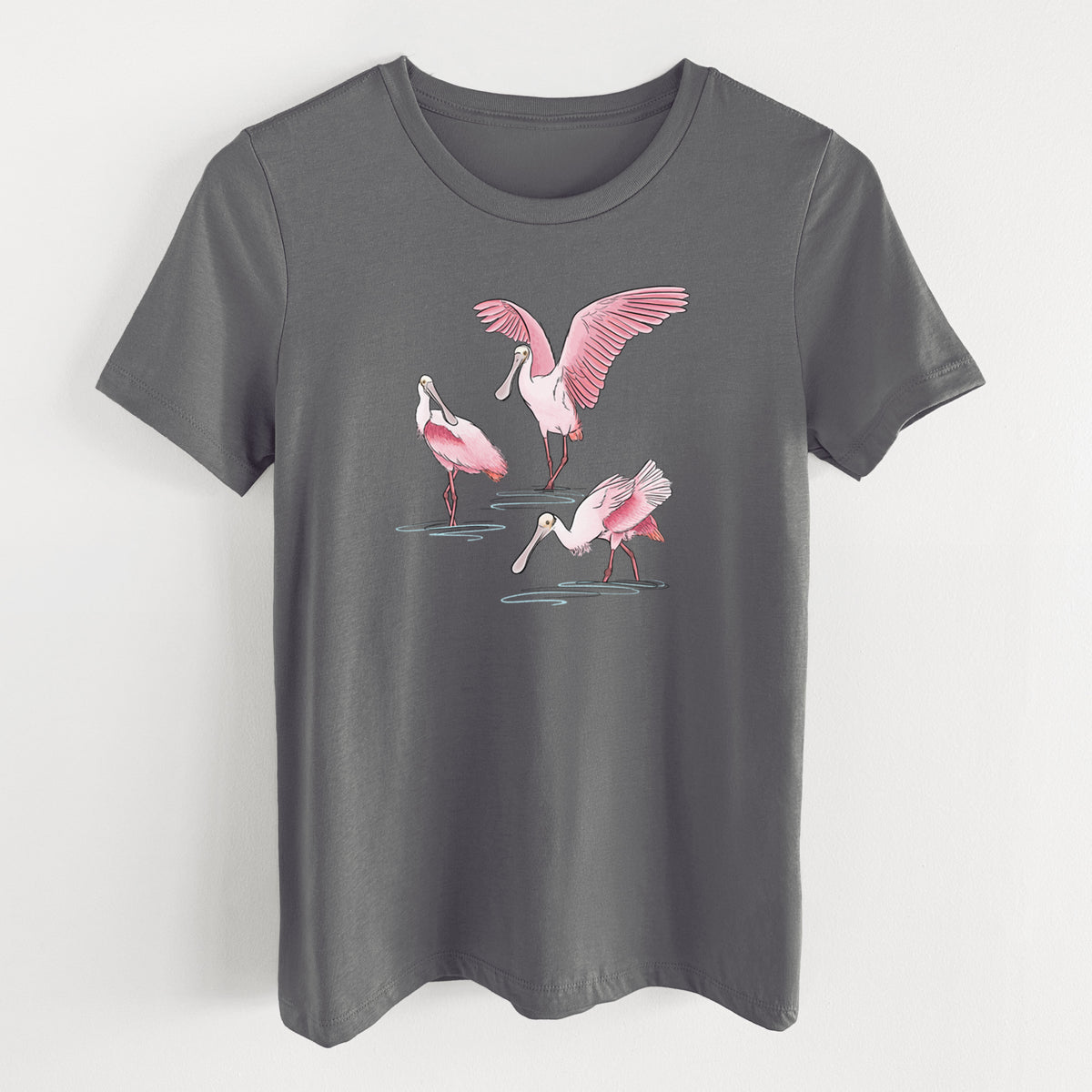 Asphalt women's relaxed fit cotton t-shirt laid flat, printed with a full-color illustration of three pink roseate spoonbills wading, one with its wings spread.
