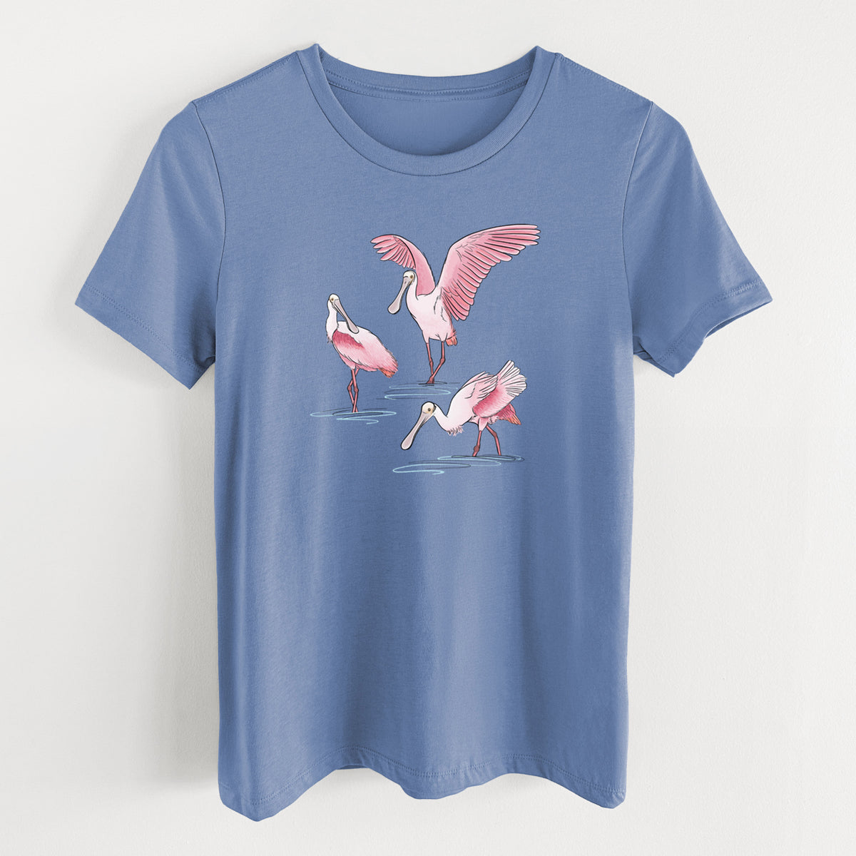 Blue bell women's relaxed fit cotton t-shirt laid flat, printed with a full-color illustration of three pink roseate spoonbills wading, one with its wings spread.