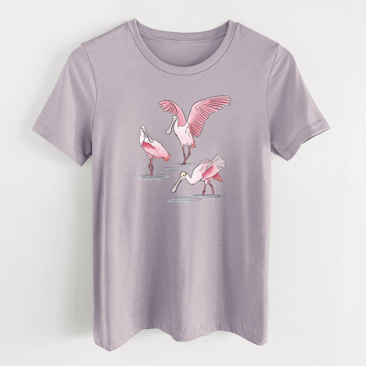 Light violet women's relaxed fit cotton t-shirt laid flat, printed with a full-color illustration of three pink roseate spoonbills wading, one with its wings spread.