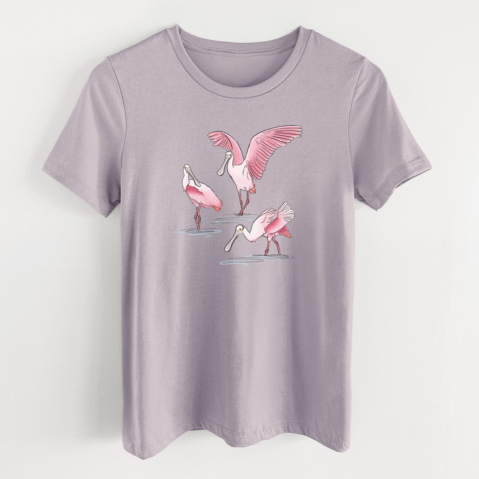 Light violet women's relaxed fit cotton t-shirt laid flat, printed with a full-color illustration of three pink roseate spoonbills wading, one with its wings spread.