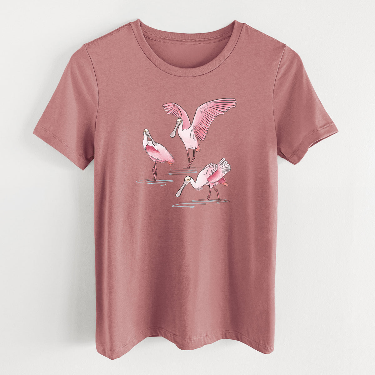 Mauve pink women's relaxed fit cotton t-shirt laid flat, printed with a full-color illustration of three pink roseate spoonbills wading, one with its wings spread.