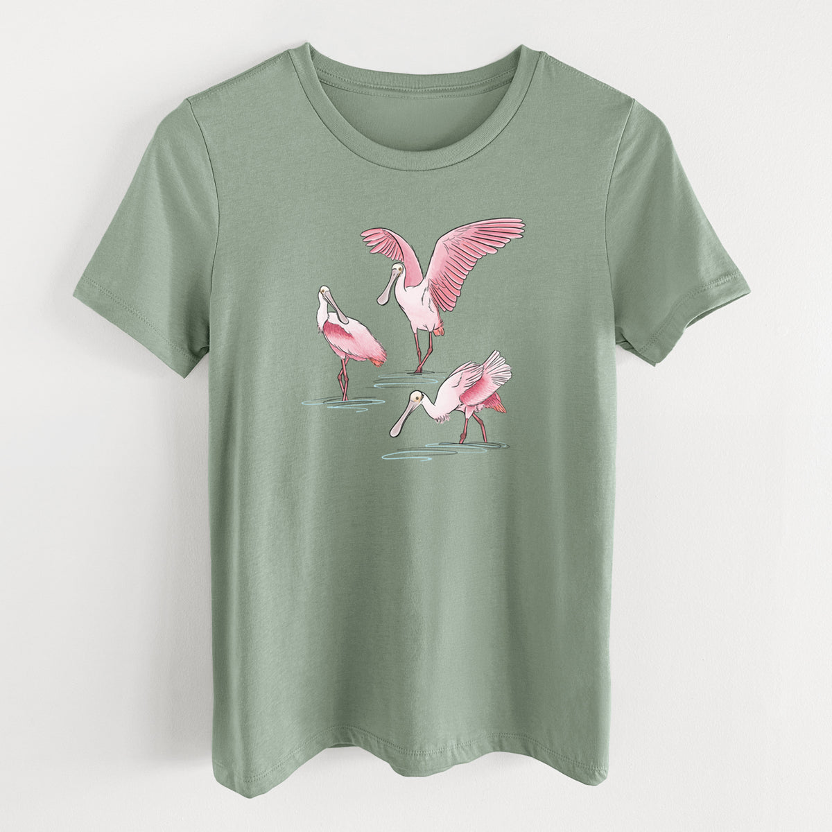 Sage green women's relaxed fit cotton t-shirt laid flat, printed with a full-color illustration of three pink roseate spoonbills wading, one with its wings spread.