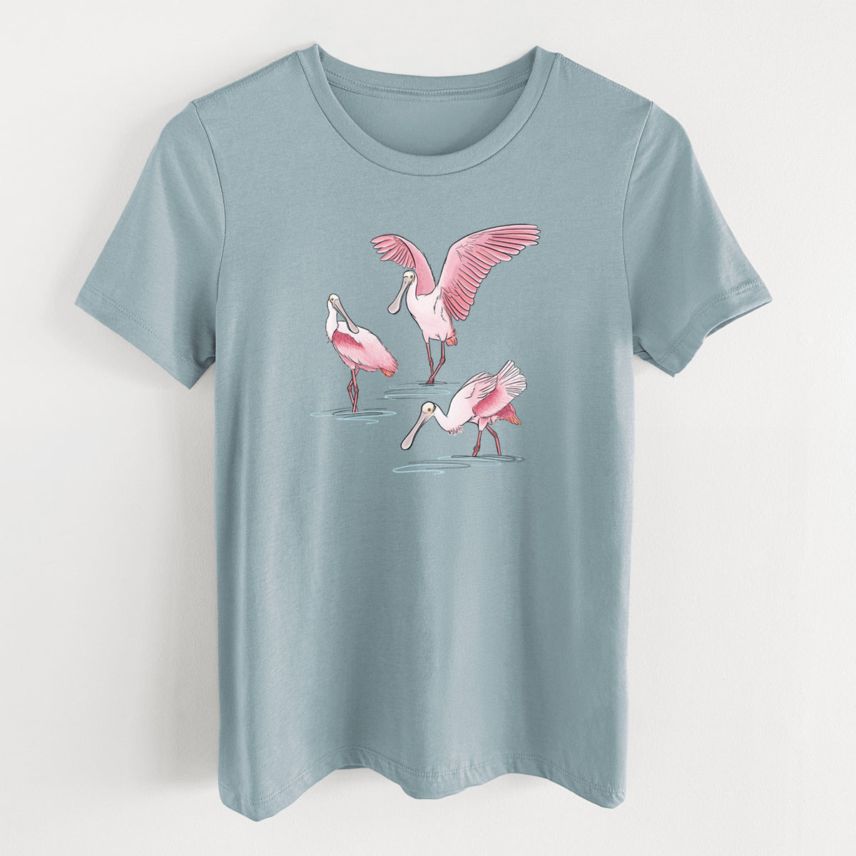 Vintage denim women's relaxed fit cotton t-shirt laid flat, printed with a full-color illustration of three pink roseate spoonbills wading, one with its wings spread.