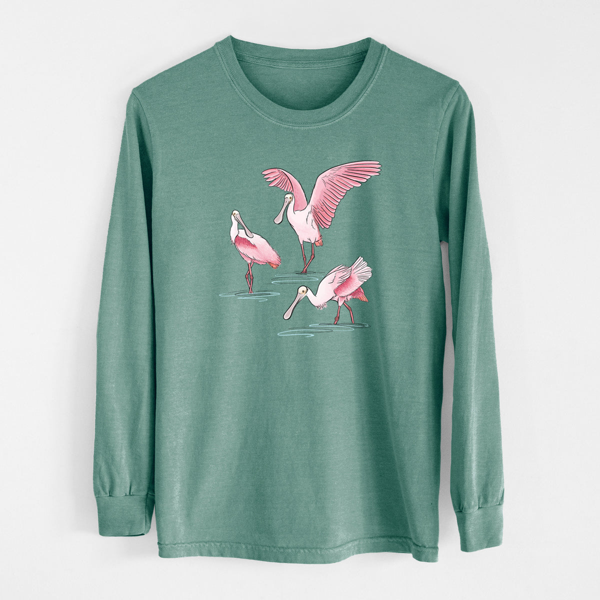 Pine green Comfort Colors long sleeve shirt laid flat, printed with a full-color illustration of three pink roseate spoonbills wading, one with its wings spread.