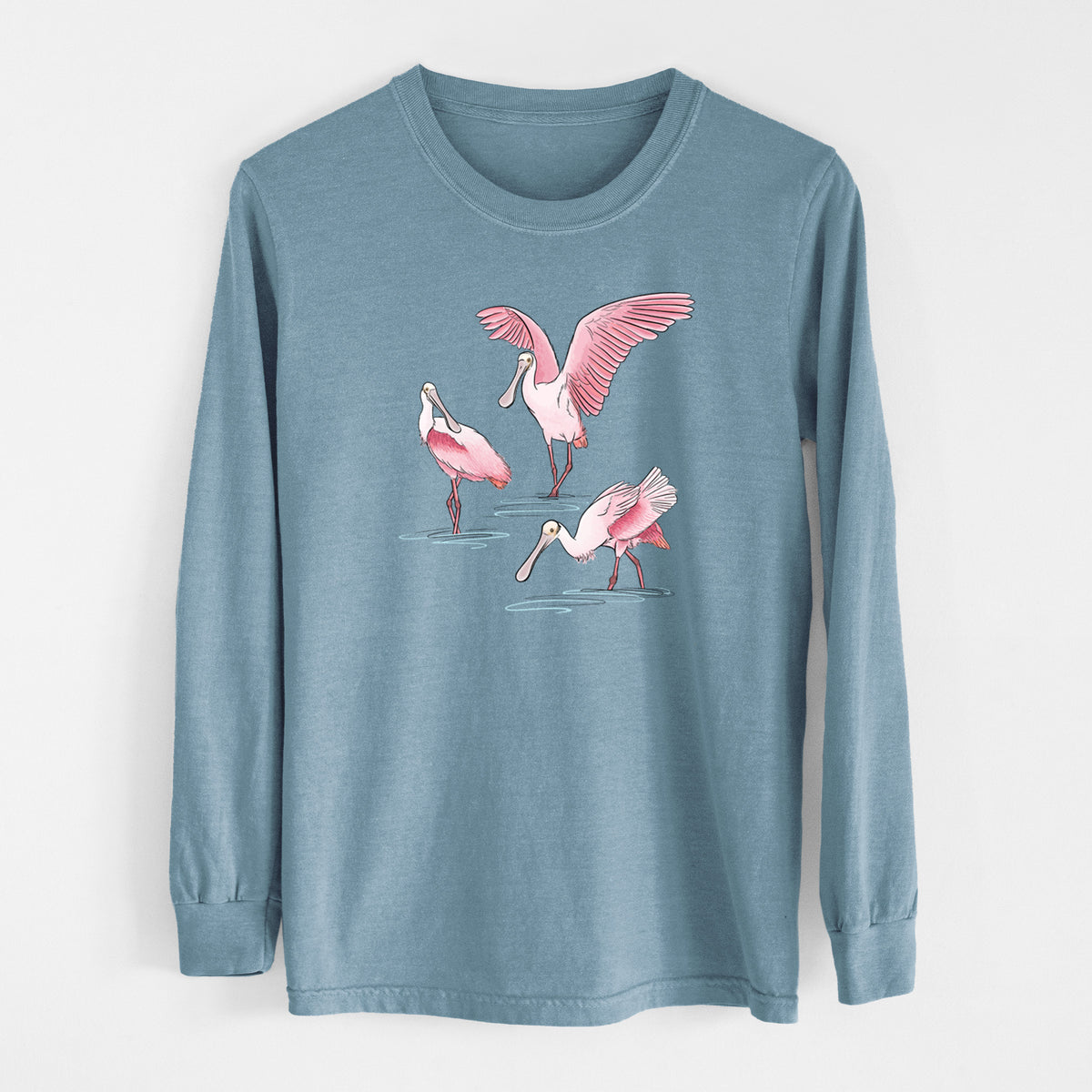 Steel blue Comfort Colors long sleeve shirt laid flat, printed with a full-color illustration of three pink roseate spoonbills wading, one with its wings spread.