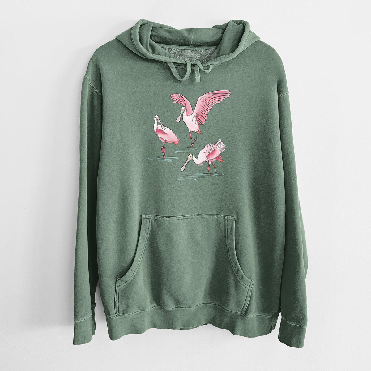 Alpine green pigment dyed hoodie laid flat, printed with a full-color illustration of three pink roseate spoonbills wading, one with its wings spread.