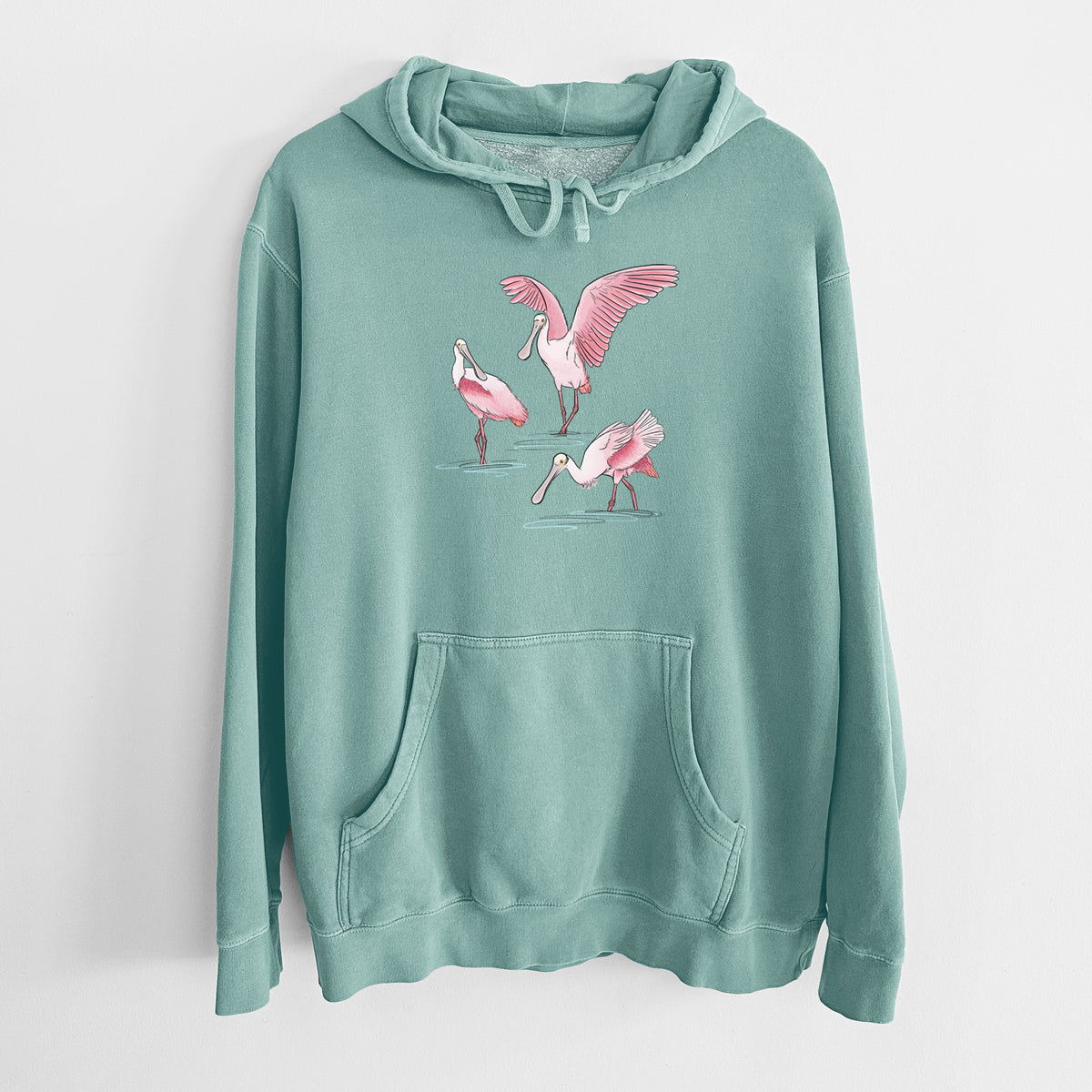 Mint green pigment dyed hoodie laid flat, printed with a full-color illustration of three pink roseate spoonbills wading, one with its wings spread.