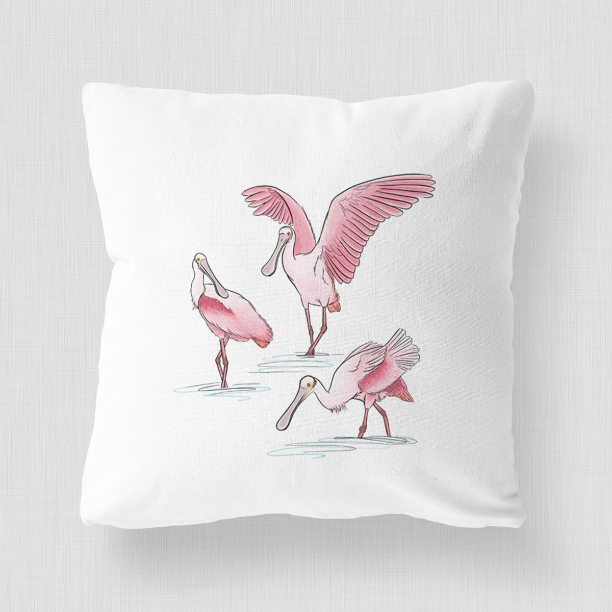 White pillow cover printed with a full-color illustration of three pink roseate spoonbills wading, one with its wings spread.