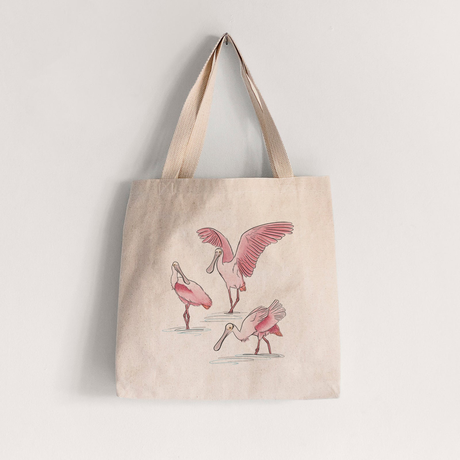 Natural canvas tote bag printed with a full-color illustration of three pink roseate spoonbills wading, one with its wings spread.