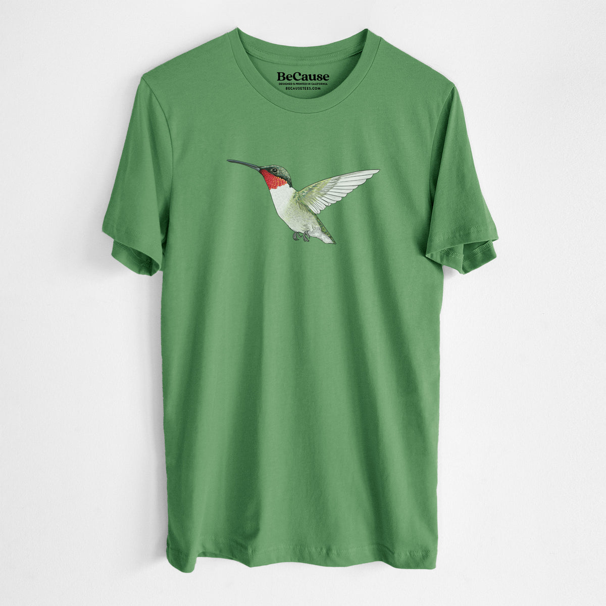 Leaf green lightweight cotton t-shirt laid flat, printed with a full-color illustration of a ruby-throated hummingbird in flight.