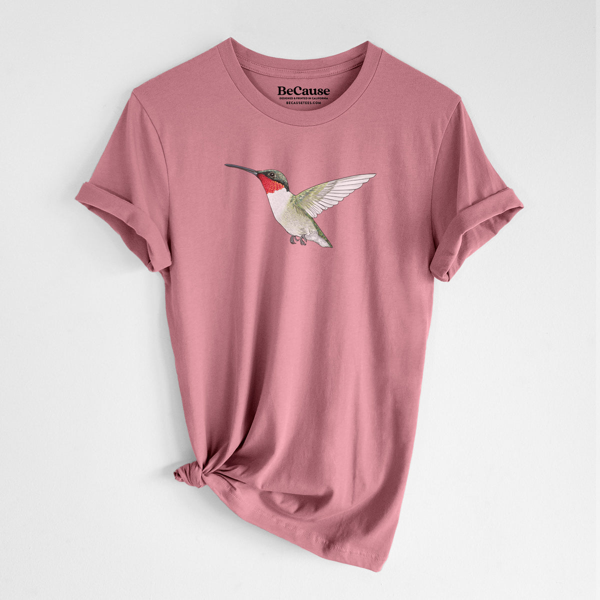 Mauve pink lightweight cotton t-shirt laid flat with the sleeves rolled, printed with a full-color illustration of a ruby-throated hummingbird in flight.