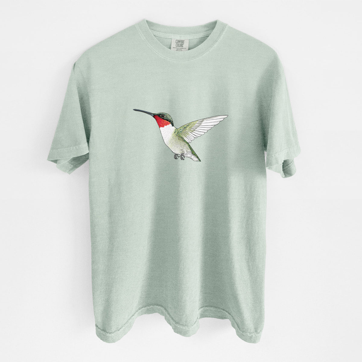 Bay green Comfort Colors t-shirt laid flat, printed with a full-color illustration of a ruby-throated hummingbird in flight.