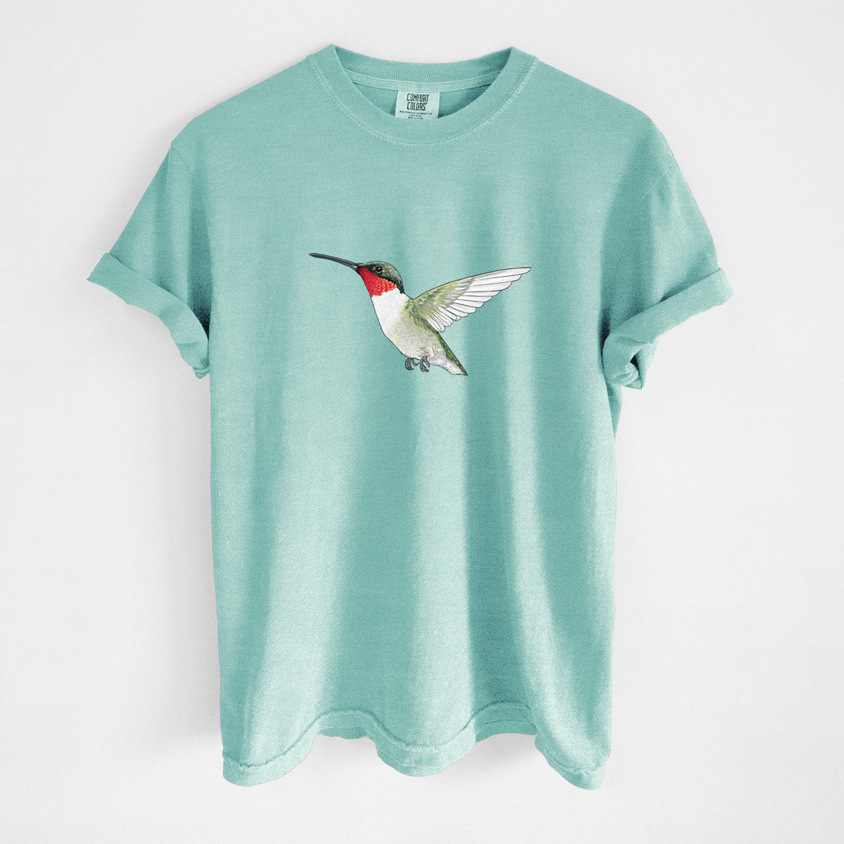 Chalky mint Comfort Colors t-shirt laid flat, printed with a full-color illustration of a ruby-throated hummingbird in flight.