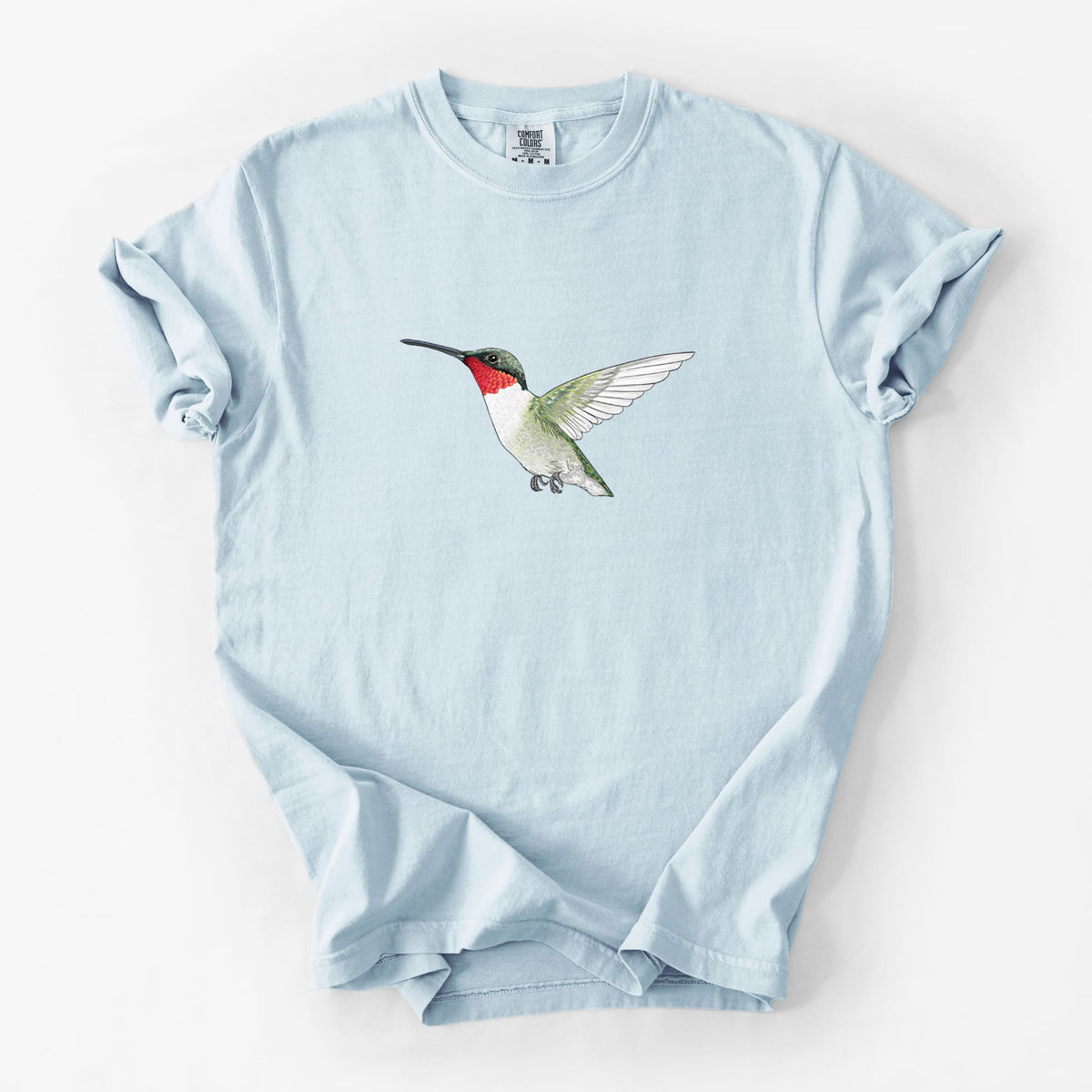 Chambray blue Comfort Colors t-shirt laid flat, printed with a full-color illustration of a ruby-throated hummingbird in flight.