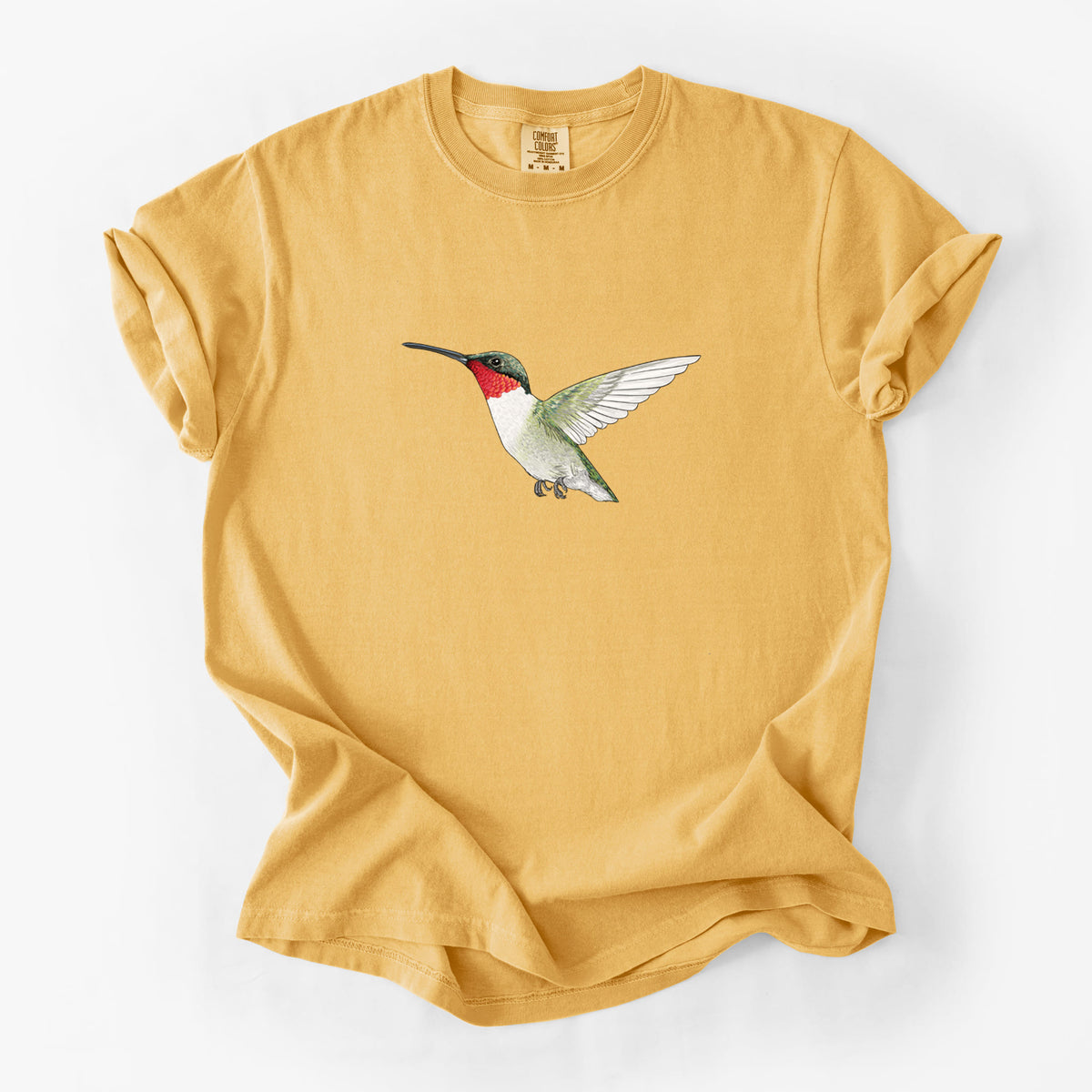 Golden wheat yellow Comfort Colors t-shirt laid flat, printed with a full-color illustration of a ruby-throated hummingbird in flight.