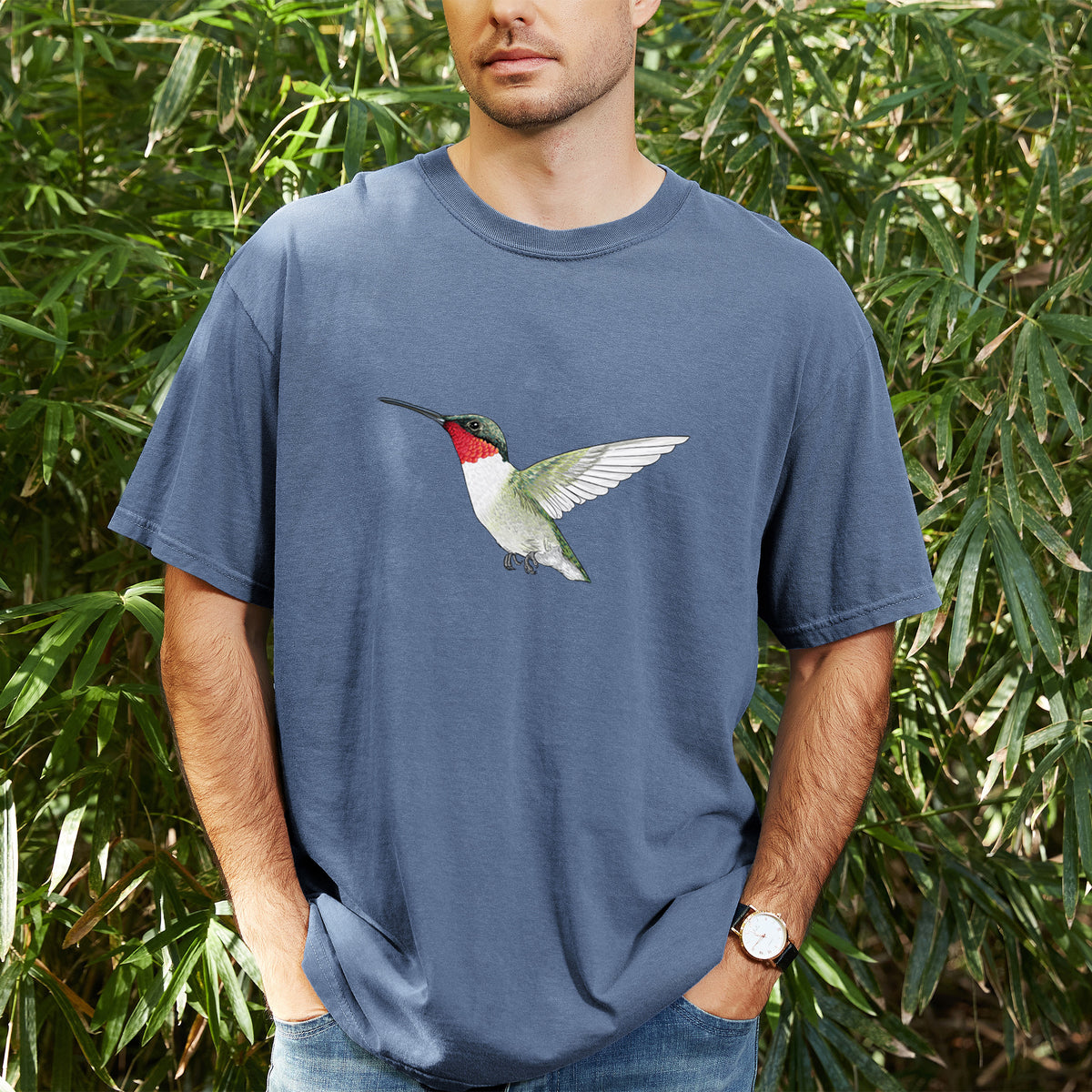 Man wearing a Comfort Colors t-shirt printed with a full-color illustration of a ruby-throated hummingbird in flight, outdoors.