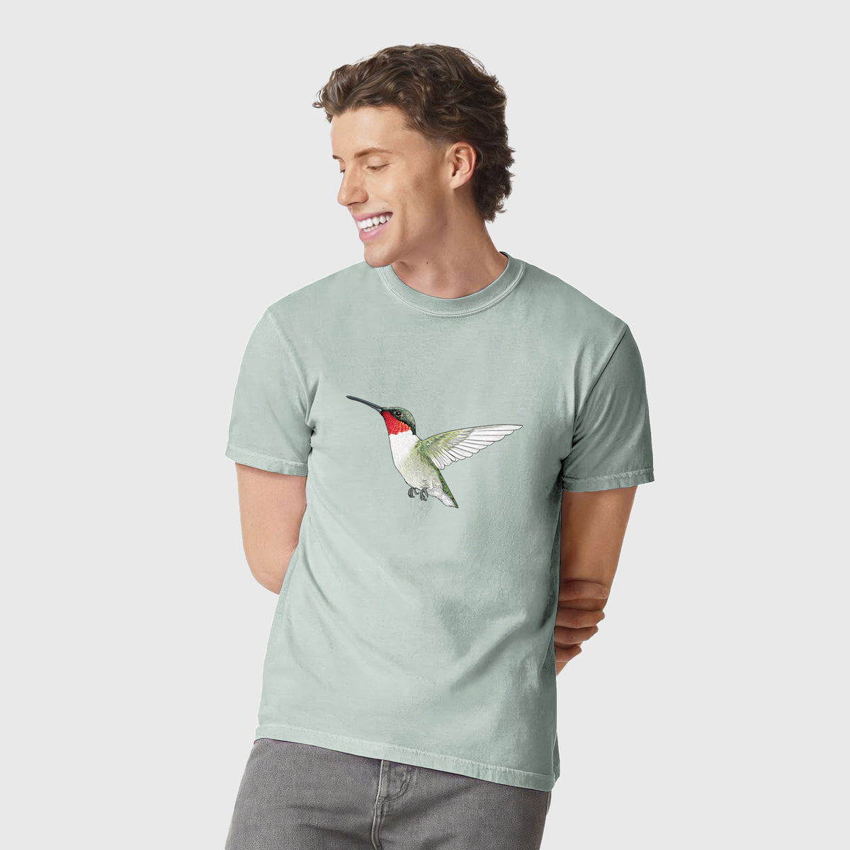 Man wearing a Comfort Colors t-shirt printed with a full-color illustration of a ruby-throated hummingbird in flight.