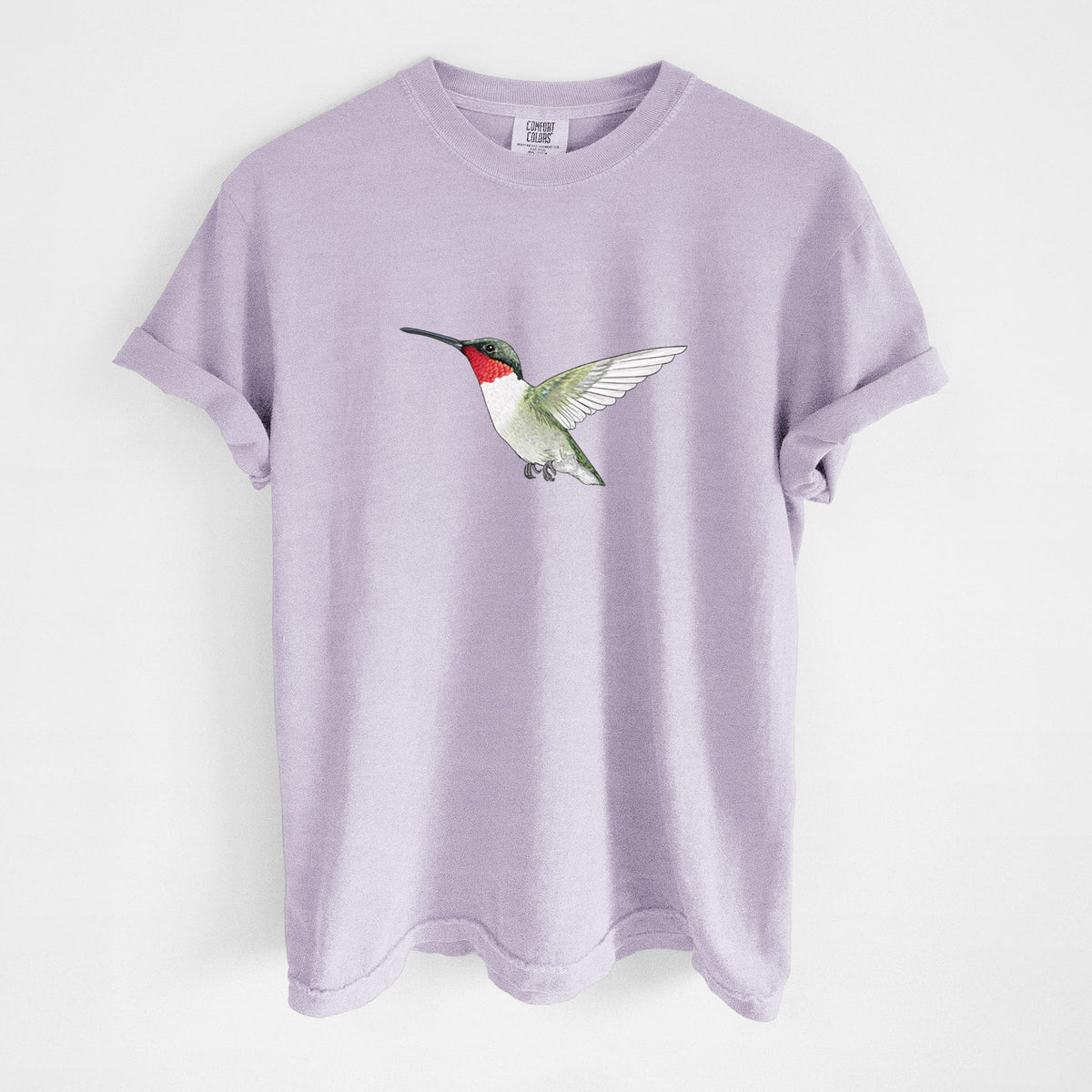 Orchid purple Comfort Colors t-shirt laid flat, printed with a full-color illustration of a ruby-throated hummingbird in flight.
