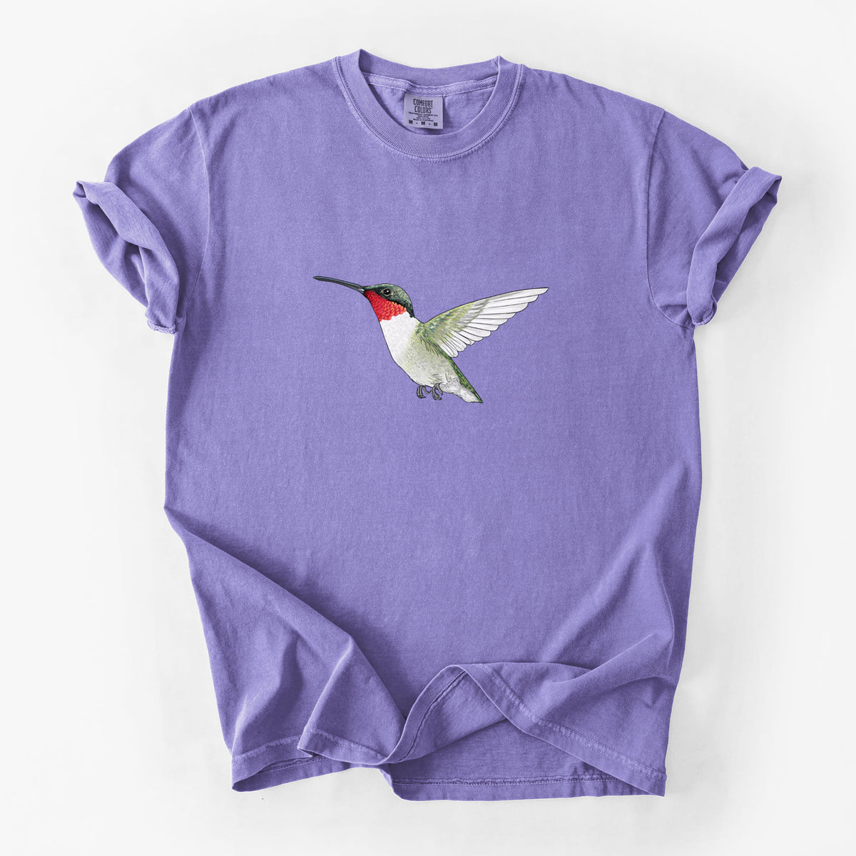 Violet purple Comfort Colors t-shirt laid flat, printed with a full-color illustration of a ruby-throated hummingbird in flight.