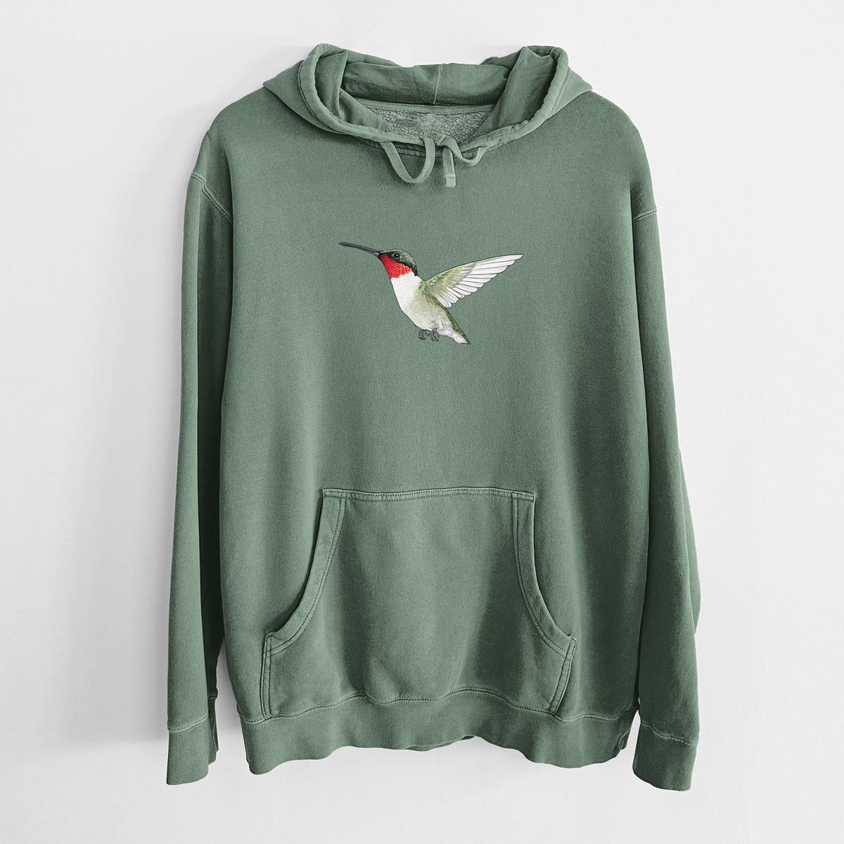 Alpine green pigment dyed hoodie laid flat, printed with a full-color illustration of a ruby-throated hummingbird in flight.