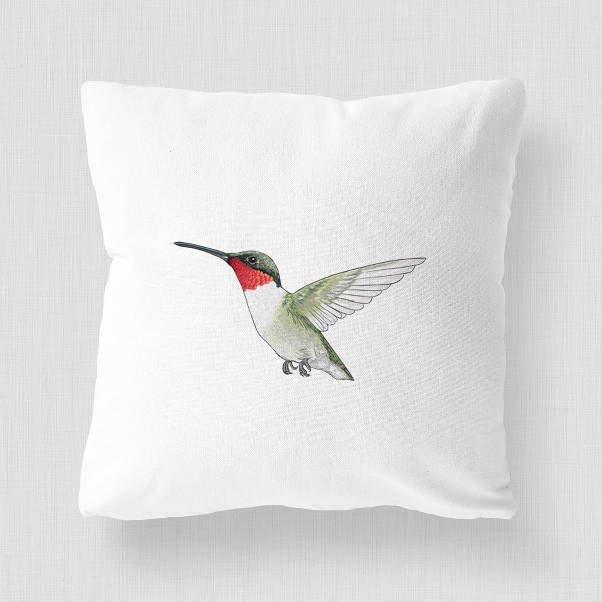 White pillow cover printed with a full-color illustration of a ruby-throated hummingbird in flight.
