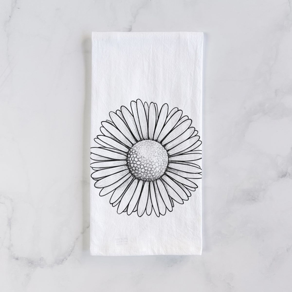White cotton tea towel laid flat on marble, printed with a detailed black ink line drawing of a single common daisy flower.